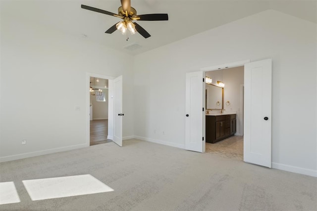 unfurnished bedroom with ensuite bathroom, ceiling fan, light colored carpet, and vaulted ceiling