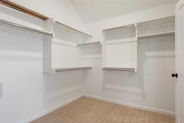 walk in closet featuring light carpet and vaulted ceiling