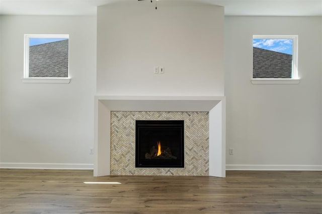 interior details with wood-type flooring and a tile fireplace