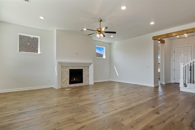 unfurnished living room with ceiling fan, light wood-type flooring, and a premium fireplace