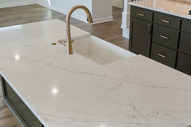 room details featuring dark hardwood / wood-style flooring, light stone counters, and sink