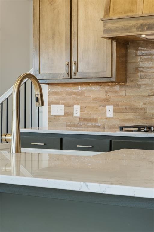 interior details featuring decorative backsplash, light stone counters, and black stovetop