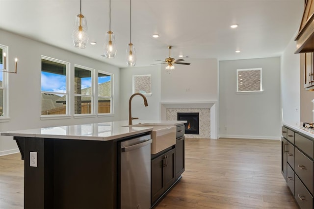 kitchen featuring stainless steel dishwasher, ceiling fan, a center island with sink, and light hardwood / wood-style flooring