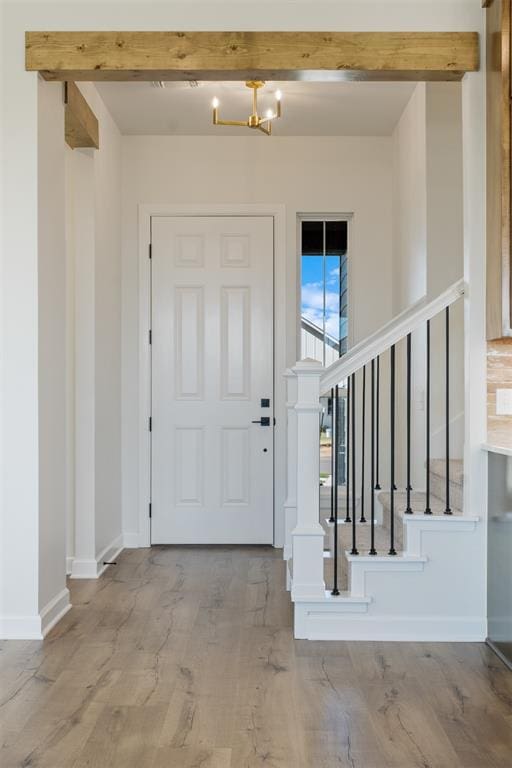 entryway featuring beamed ceiling, light hardwood / wood-style floors, and a chandelier