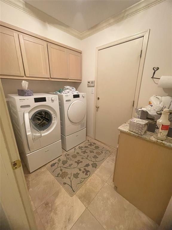 washroom featuring washing machine and dryer, light tile patterned floors, cabinets, and ornamental molding