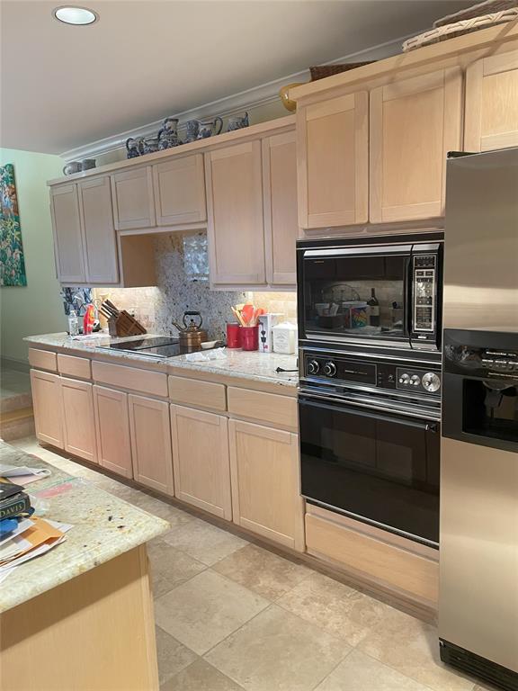 kitchen with decorative backsplash, light brown cabinetry, light tile patterned flooring, and black appliances