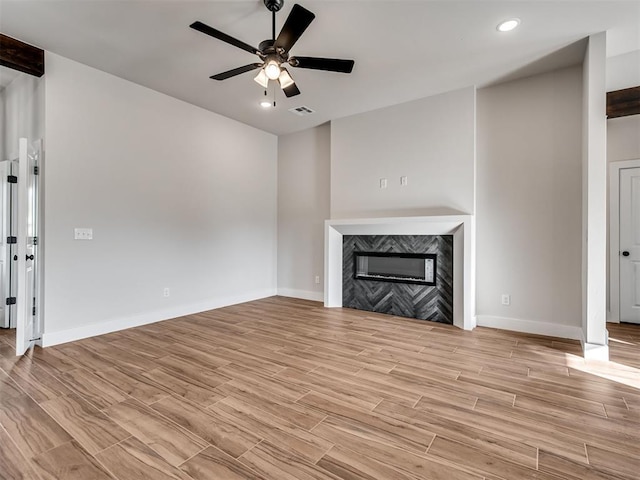 unfurnished living room with ceiling fan, light wood-type flooring, and a premium fireplace