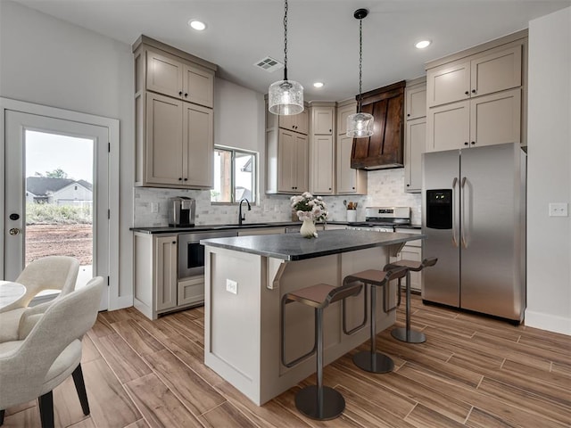 kitchen featuring appliances with stainless steel finishes, decorative light fixtures, plenty of natural light, and wood-type flooring