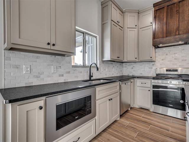 kitchen featuring decorative backsplash, custom range hood, stainless steel appliances, sink, and light hardwood / wood-style flooring