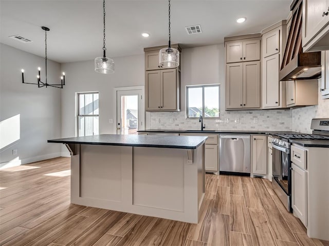 kitchen featuring stainless steel appliances, gray cabinets, hanging light fixtures, and a healthy amount of sunlight