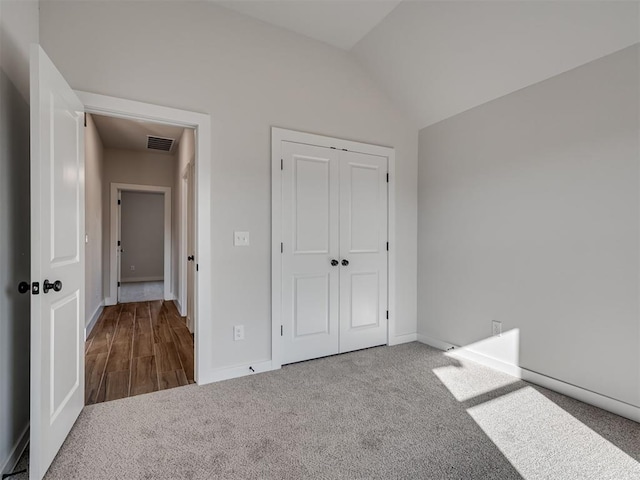 unfurnished bedroom featuring lofted ceiling, carpet floors, and a closet