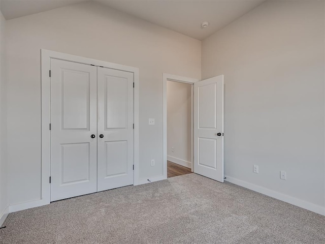 unfurnished bedroom with carpet, vaulted ceiling, and a closet