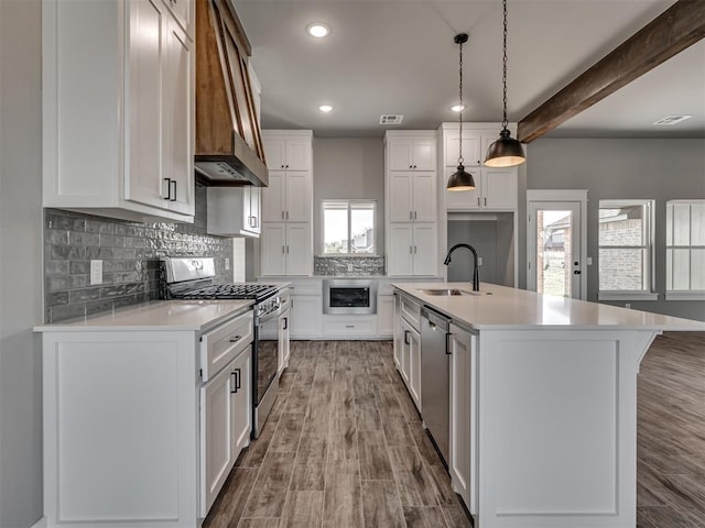 kitchen featuring appliances with stainless steel finishes, sink, pendant lighting, white cabinets, and an island with sink