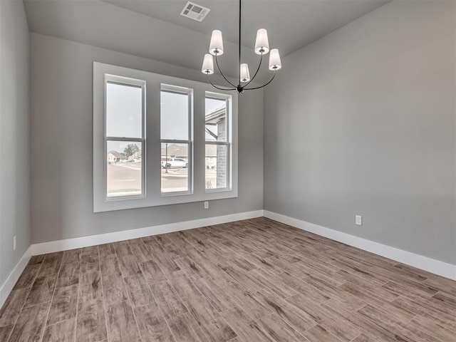 unfurnished room with light hardwood / wood-style floors and a chandelier