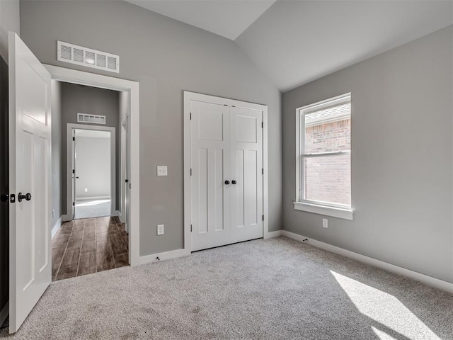 unfurnished bedroom featuring a closet, carpet, and vaulted ceiling