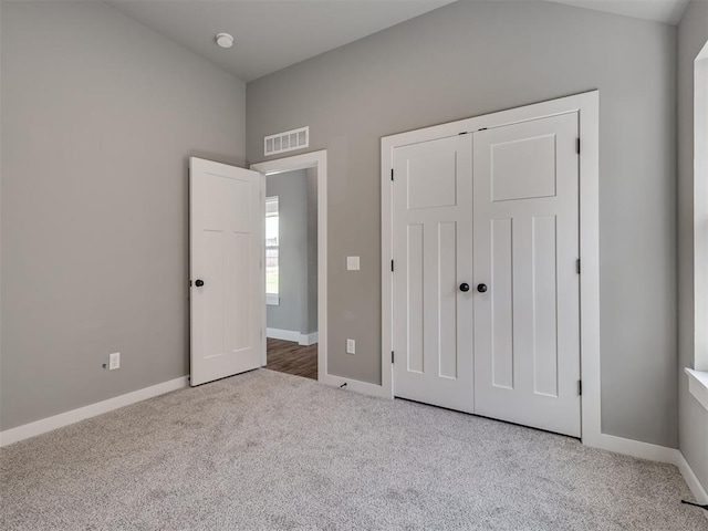 unfurnished bedroom with light colored carpet and a closet