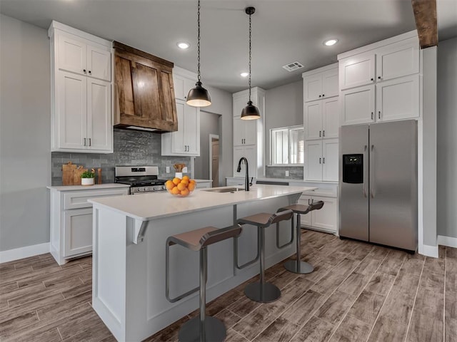 kitchen featuring light wood-type flooring, stainless steel appliances, sink, a center island with sink, and white cabinetry