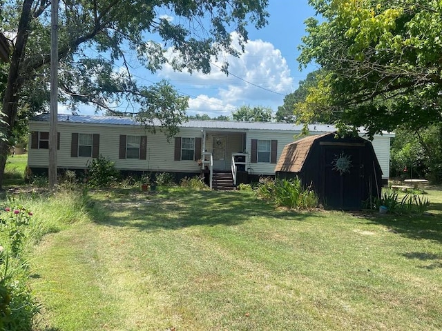 view of front of house featuring a front lawn and a storage shed