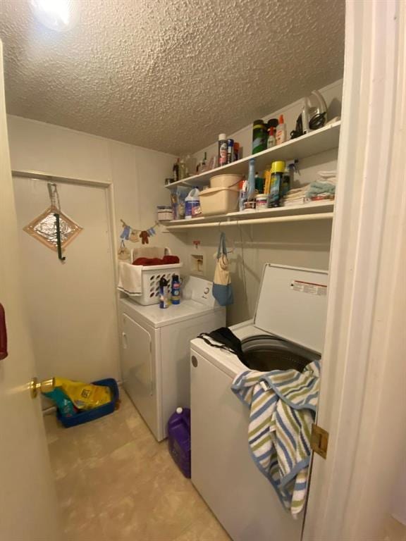 washroom with washing machine and clothes dryer and a textured ceiling