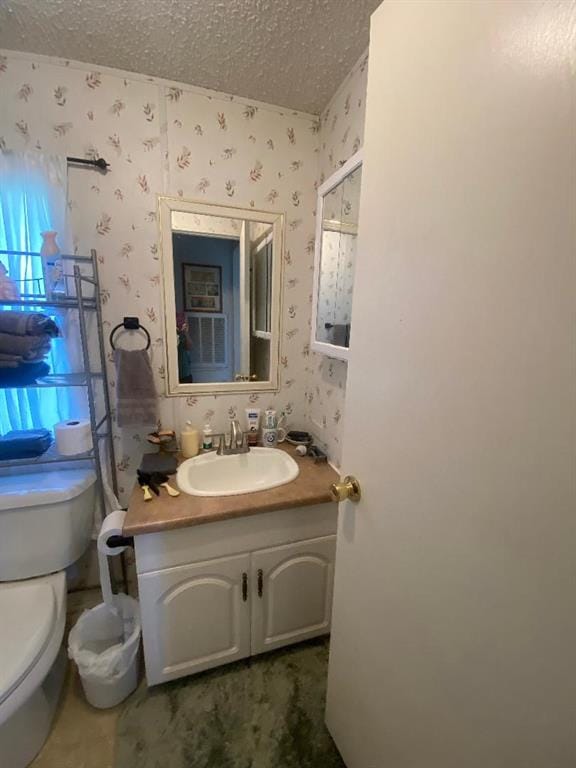 bathroom with vanity, toilet, and a textured ceiling