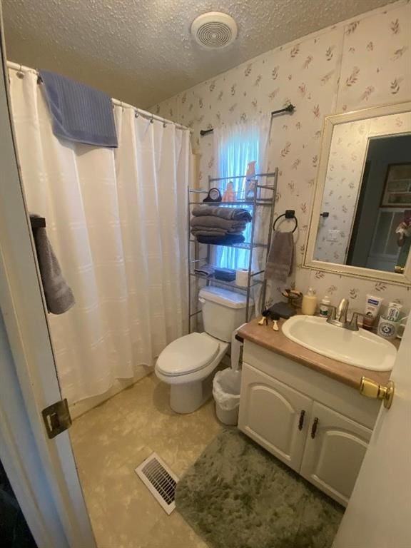 bathroom featuring vanity, toilet, a textured ceiling, and walk in shower