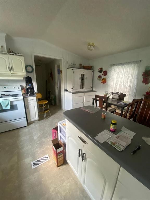 kitchen featuring electric stove, white cabinets, and vaulted ceiling