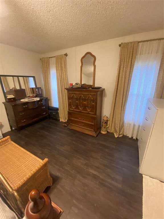 bedroom with multiple windows, dark wood-type flooring, and a textured ceiling