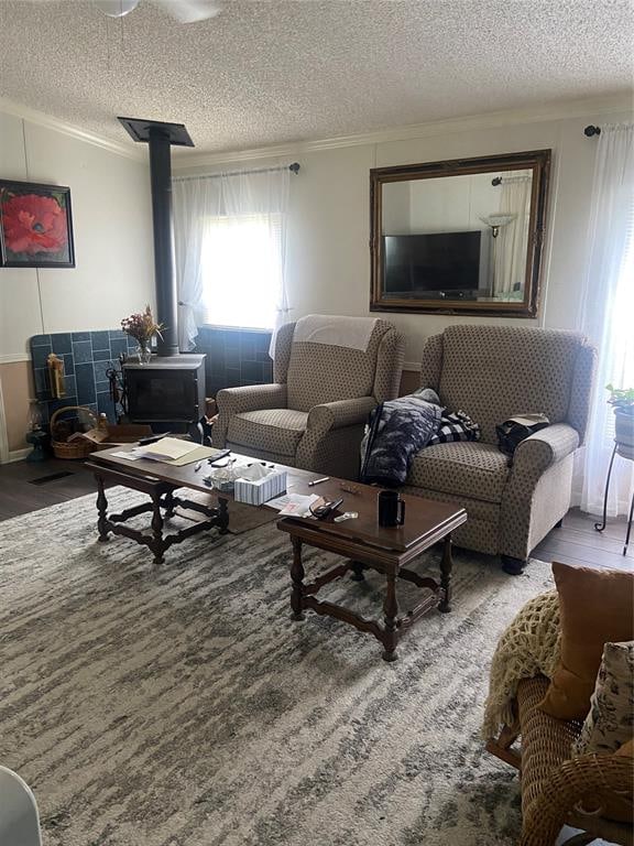 living room featuring hardwood / wood-style floors, a textured ceiling, a wood stove, and ornamental molding