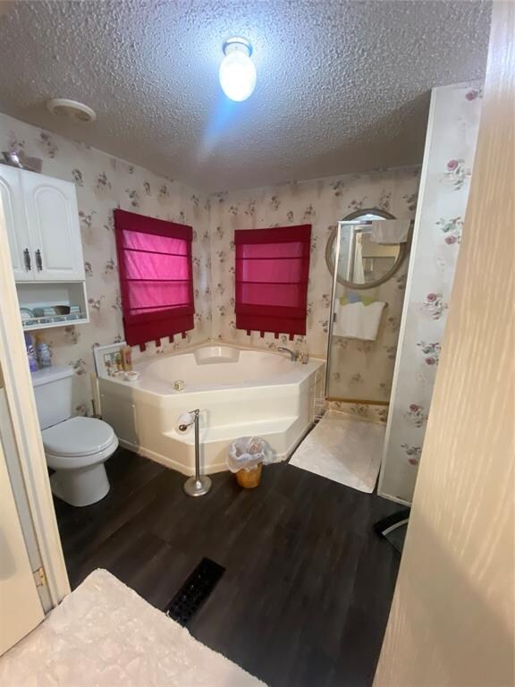 bathroom with hardwood / wood-style flooring, separate shower and tub, toilet, and a textured ceiling