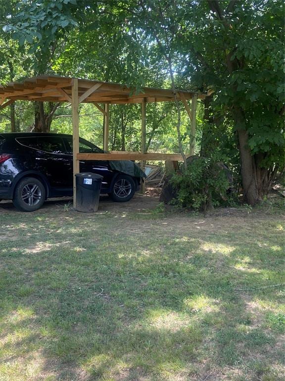 view of parking / parking lot featuring a carport and a lawn