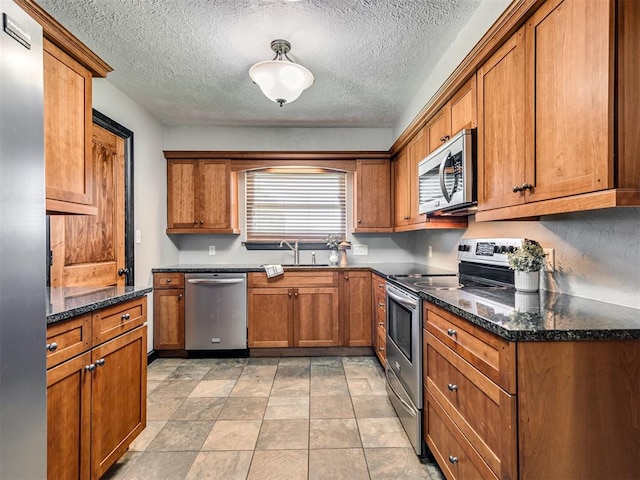 kitchen featuring sink, dark stone countertops, a textured ceiling, and appliances with stainless steel finishes