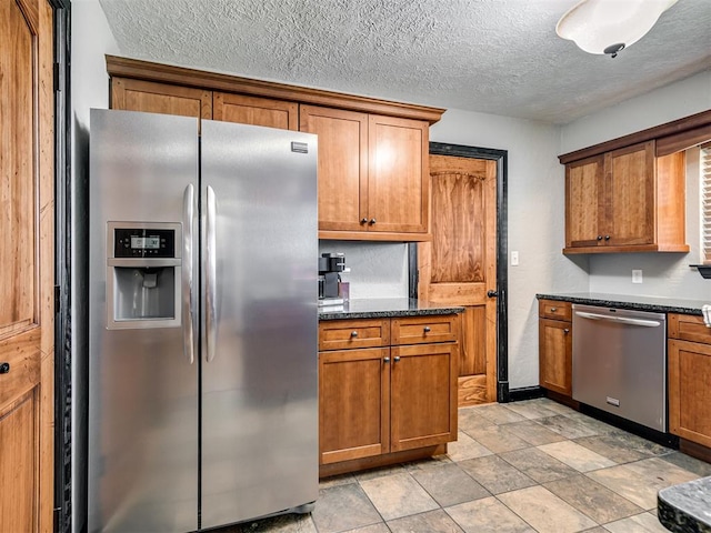 kitchen featuring a textured ceiling, dark stone countertops, and stainless steel appliances