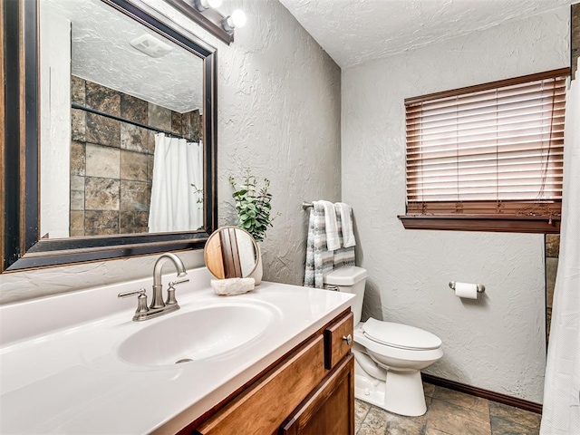 bathroom with walk in shower, vanity, a textured ceiling, and toilet