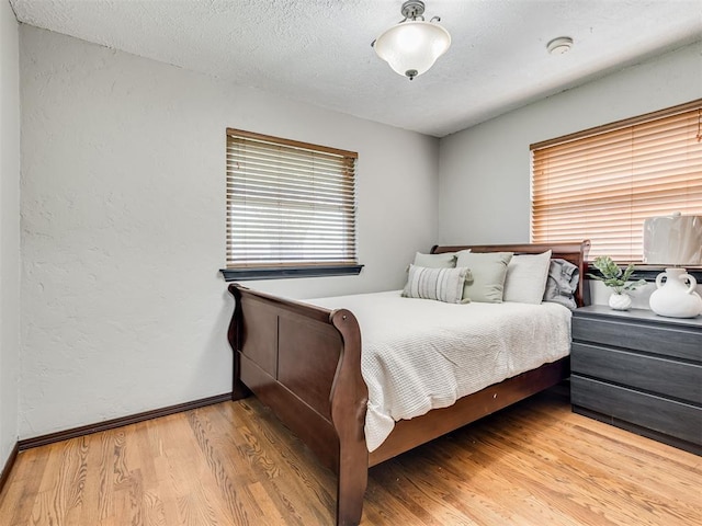 bedroom featuring hardwood / wood-style flooring, a textured ceiling, and multiple windows