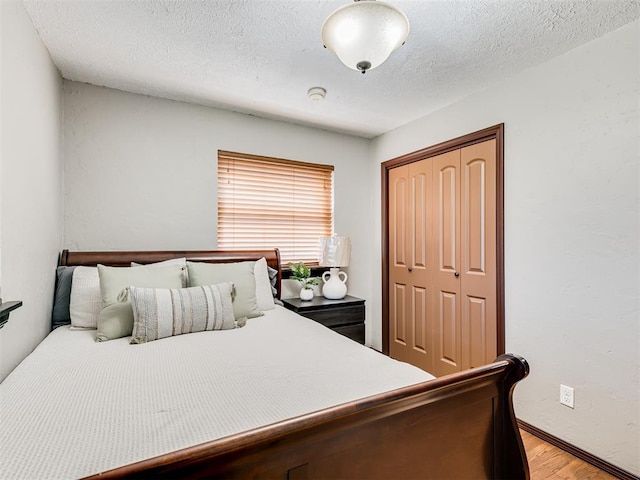 bedroom featuring light wood-type flooring, a textured ceiling, and a closet