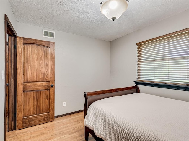 bedroom featuring light hardwood / wood-style flooring and a textured ceiling