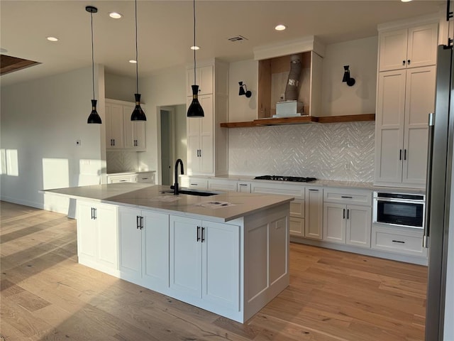 kitchen featuring a center island with sink, light hardwood / wood-style floors, and white cabinets