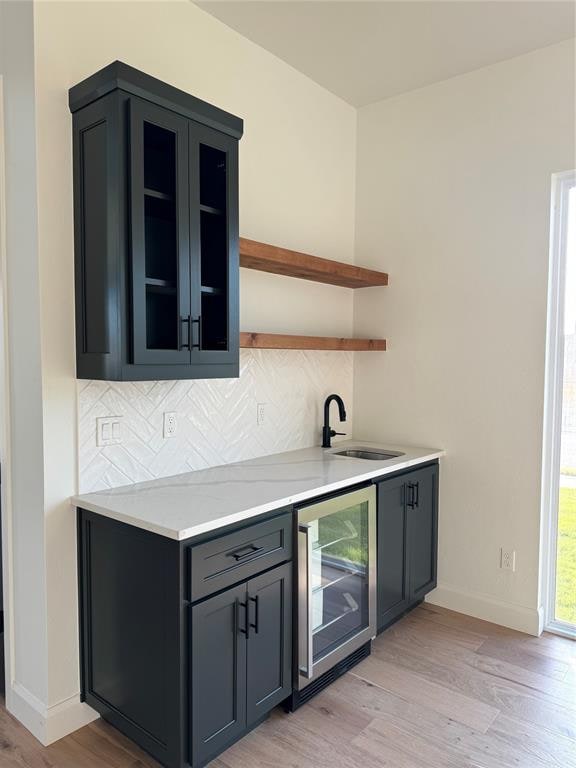 bar with light hardwood / wood-style floors, sink, wine cooler, and tasteful backsplash