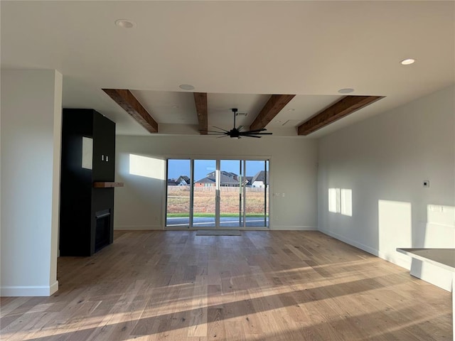 unfurnished living room with a mountain view, beam ceiling, light hardwood / wood-style floors, and ceiling fan