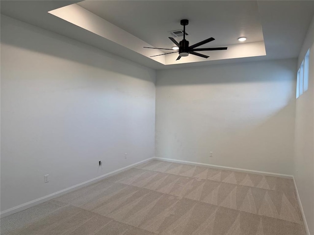 carpeted empty room featuring a raised ceiling and ceiling fan