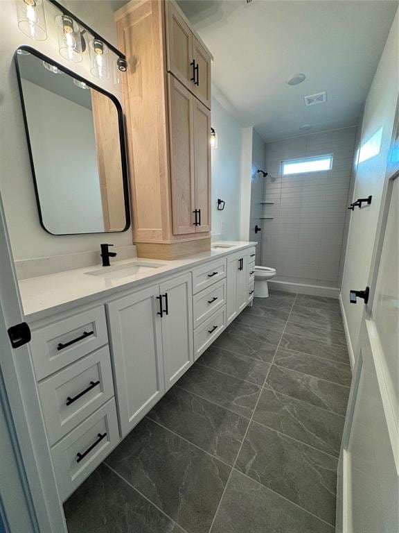 bathroom with vanity, toilet, and tiled shower