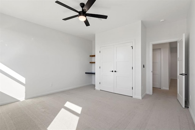 unfurnished bedroom with baseboards, light carpet, a closet, and ceiling fan