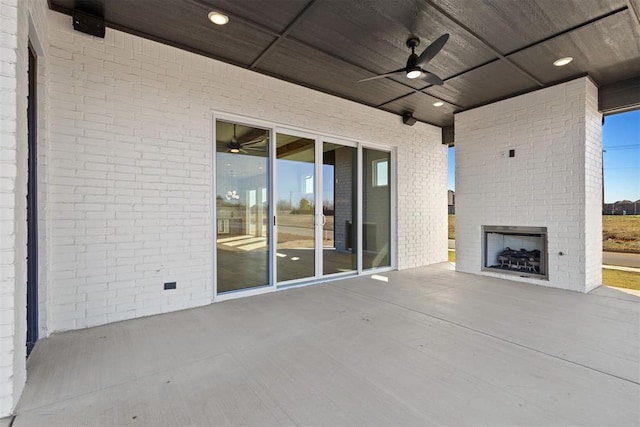 view of patio / terrace with a ceiling fan and an outdoor brick fireplace