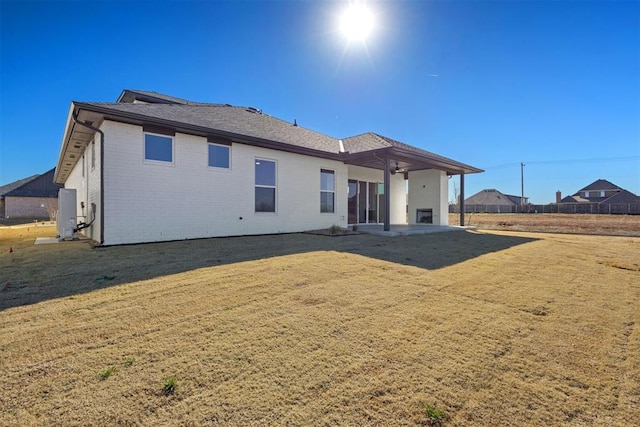 rear view of house featuring a patio, a lawn, and brick siding