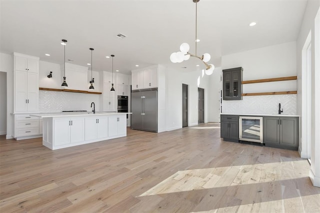 kitchen featuring visible vents, open shelves, stainless steel appliances, wine cooler, and light wood-style floors