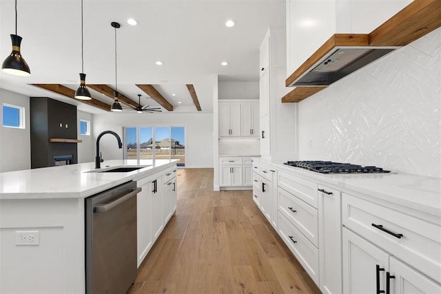 kitchen featuring a sink, backsplash, white cabinetry, light wood-style floors, and appliances with stainless steel finishes