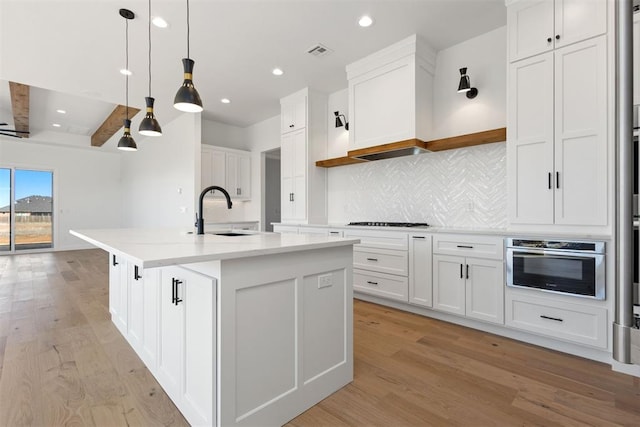 kitchen with oven, light wood-type flooring, a sink, open shelves, and tasteful backsplash