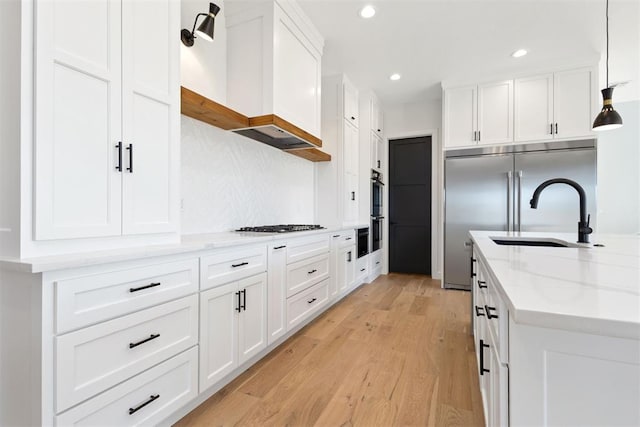 kitchen with light wood-type flooring, light stone countertops, stainless steel appliances, and white cabinetry