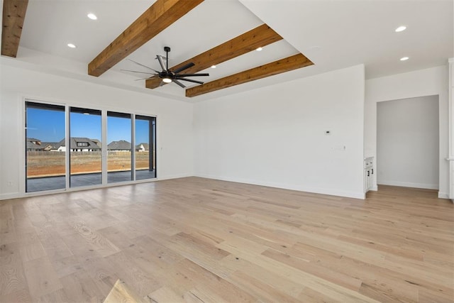 spare room with baseboards, beam ceiling, and light wood-style floors