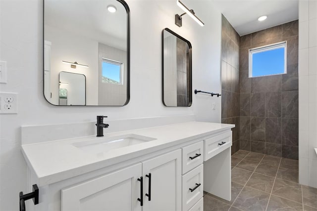 bathroom with recessed lighting, vanity, and a tile shower